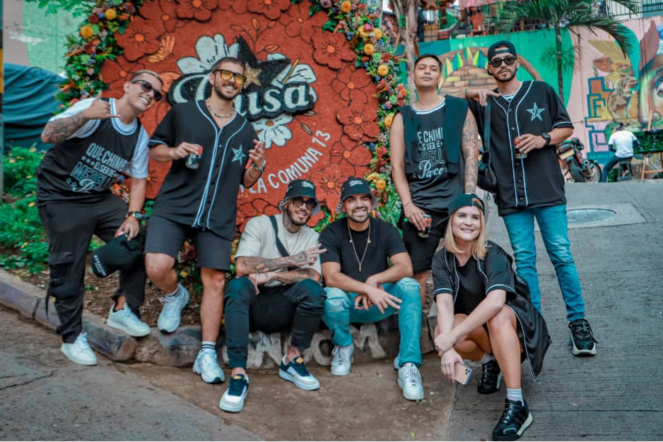 Jóvenes en Comuna 13 con una silleta detrás y el barrio de fondo.